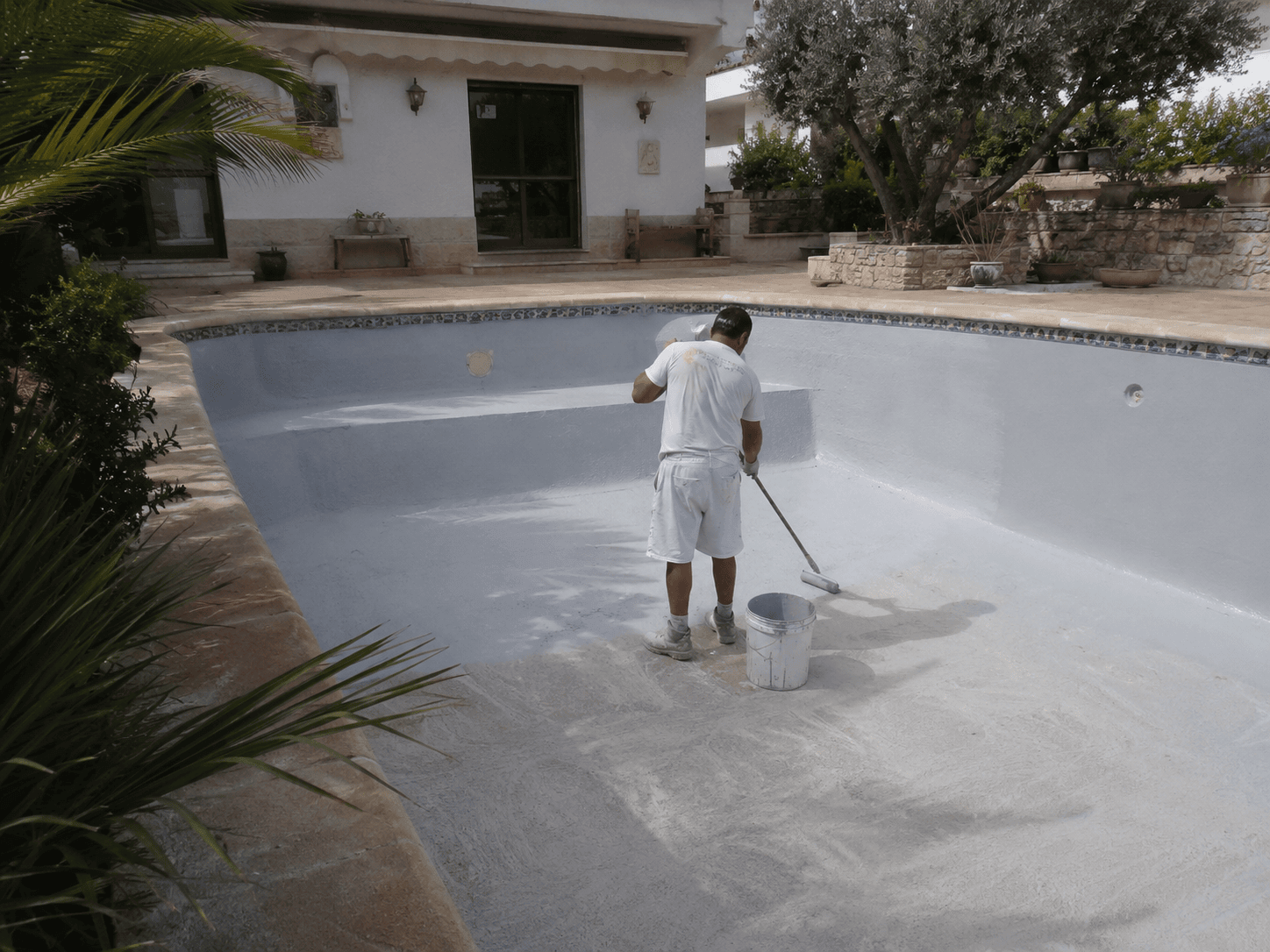 Operario aplicando un revestimiento impermeabilizante en el interior de una piscina privada en Altea